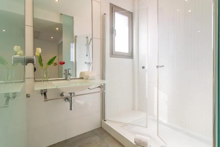 A bright bathroom with a glass shower and a sink beneath a mirror.