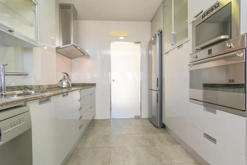 A bright modern kitchen with white cabinetry and built-in appliances.