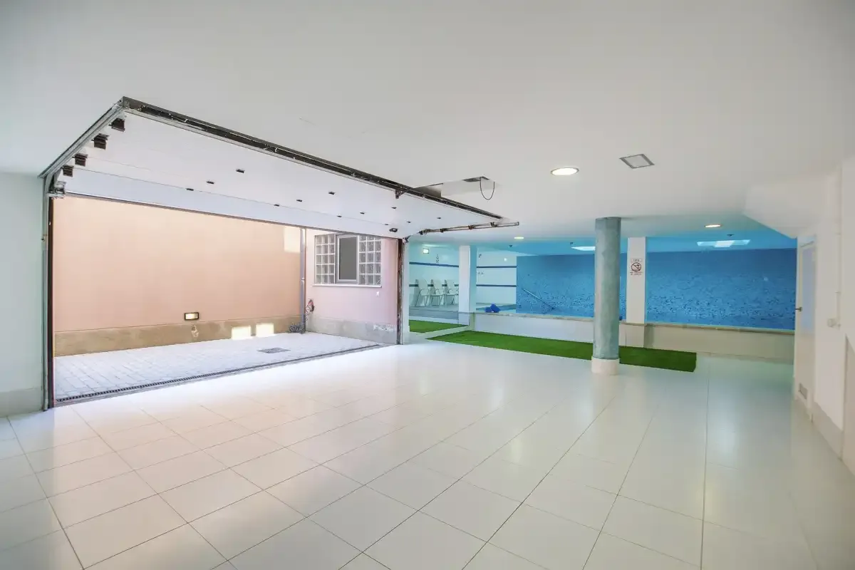 A spacious indoor area opens onto a small pool bordered by blue walls.
