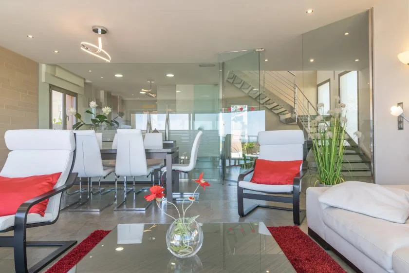 A modern living and dining area with seating, a dining table, and a staircase.