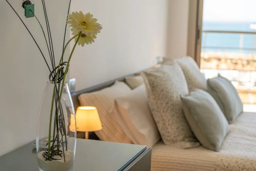 A bright living room with a sofa, cushions, and a small illuminated table lamp.