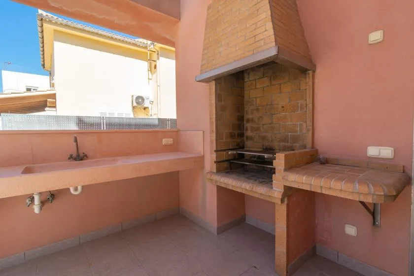 A covered outdoor cooking area with a built-in grill and sink.