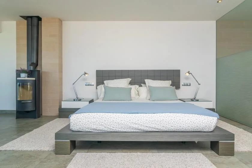 A modern bedroom with a low platform bed and matching bedside lamps.