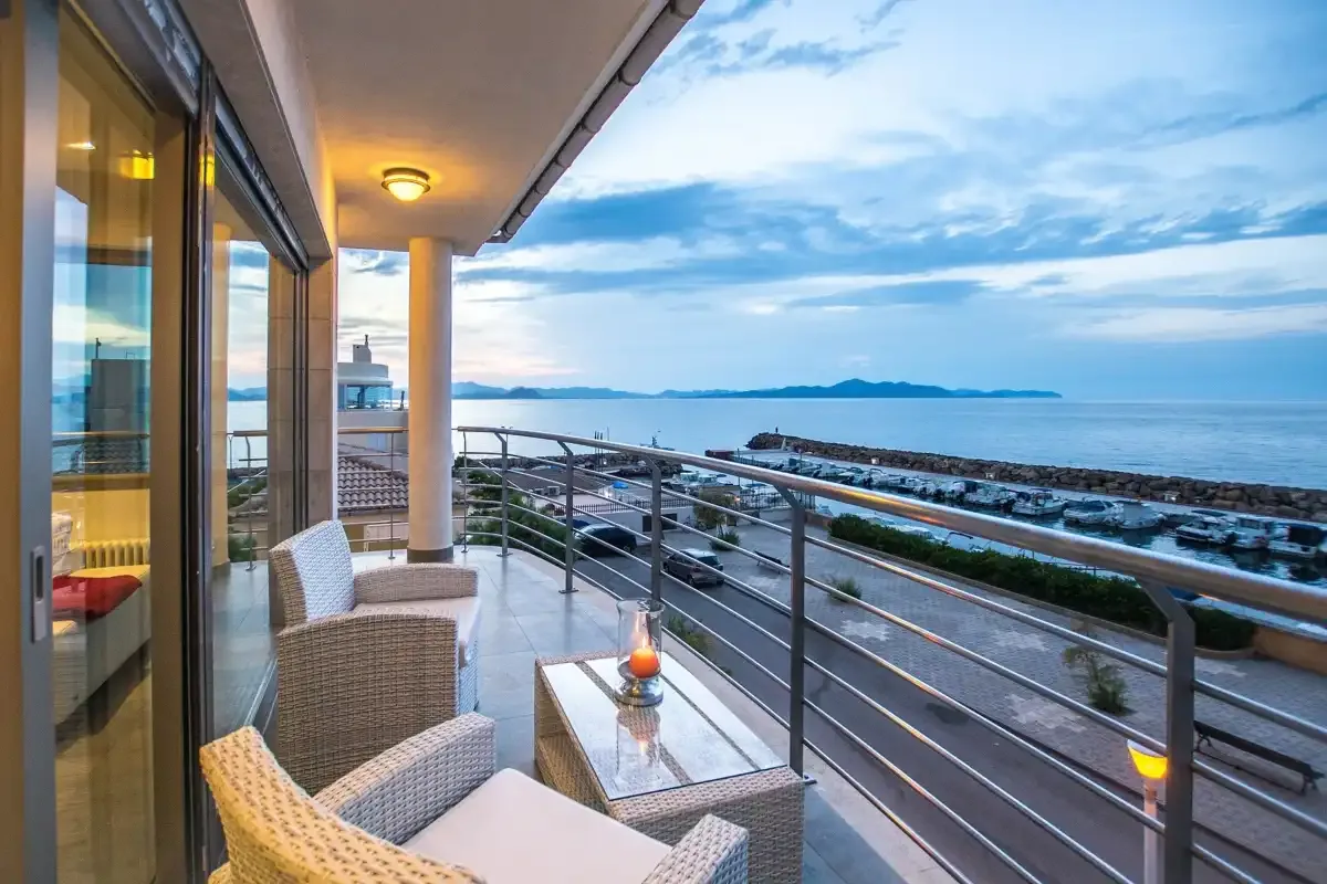 A furnished balcony overlooks the coastline and water.