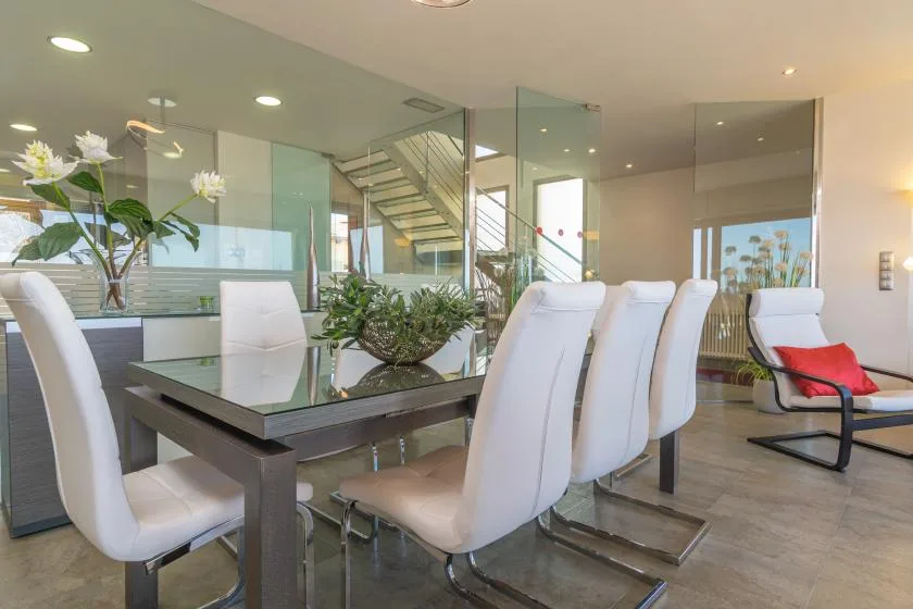 A dining area with white seating around a glass-topped table.
