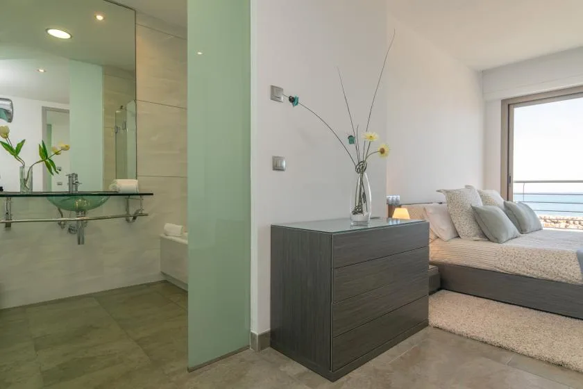 A bedroom with a bed beside a glass-walled bathroom.