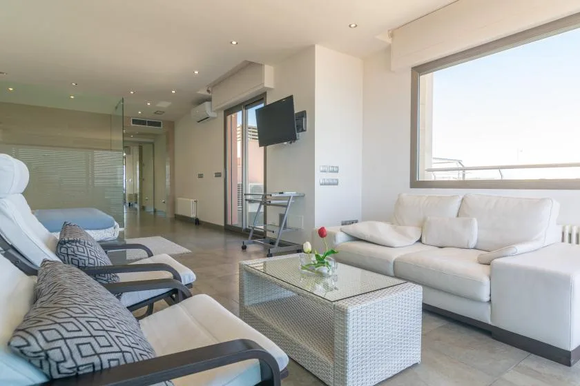 A bright living room with seating arranged around a glass coffee table.