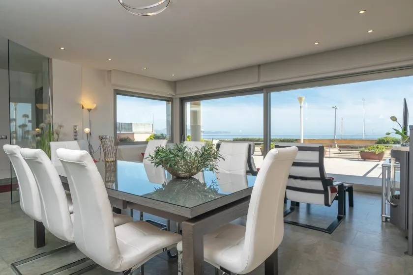 A bright dining area opens onto a terrace with a view of the sea.