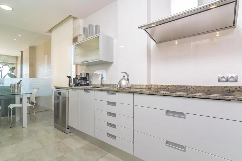 A bright modern kitchen with white cabinets and a dining area.