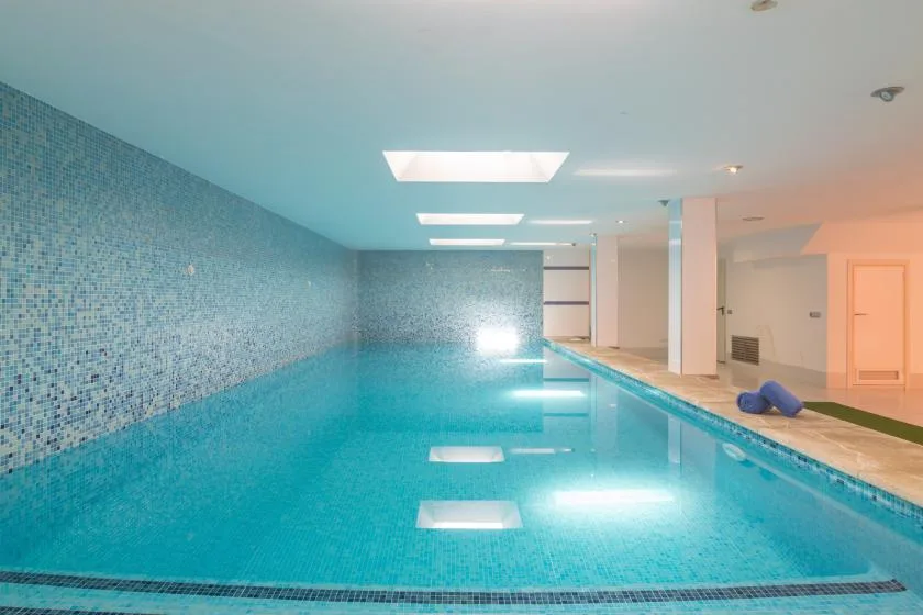 An indoor swimming pool with tiled walls and bright ceiling lights.