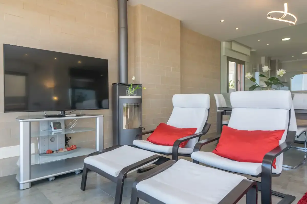 A bright living room with two reclining seats, a television, and a glass door.