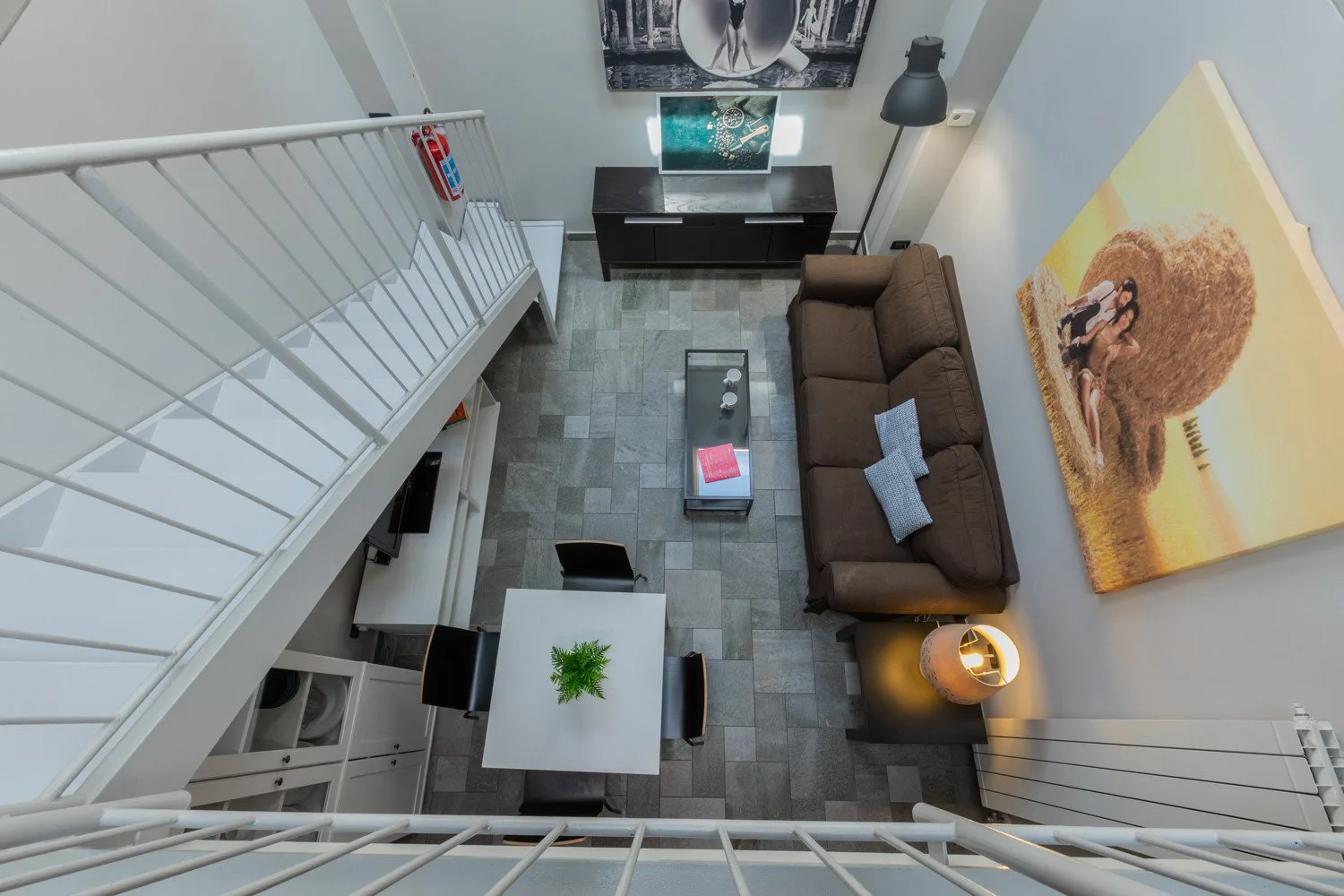 A loft living room with a brown sofa, coffee table, and wall art.