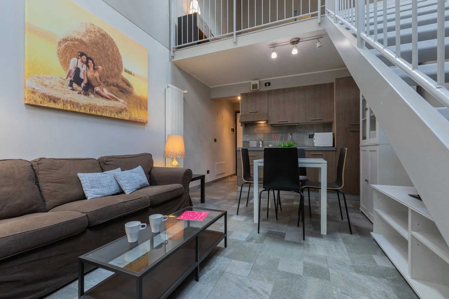 A living and dining area with a sofa, table, and staircase.