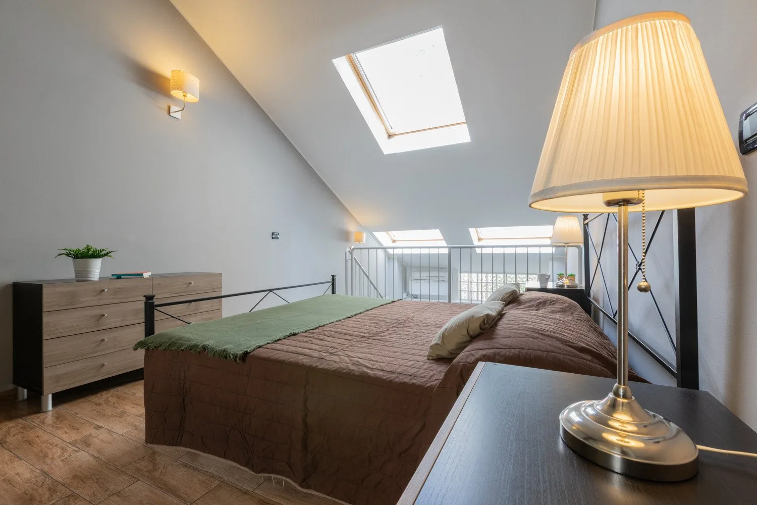 A bedroom with a bed beneath a sloped ceiling and skylight.