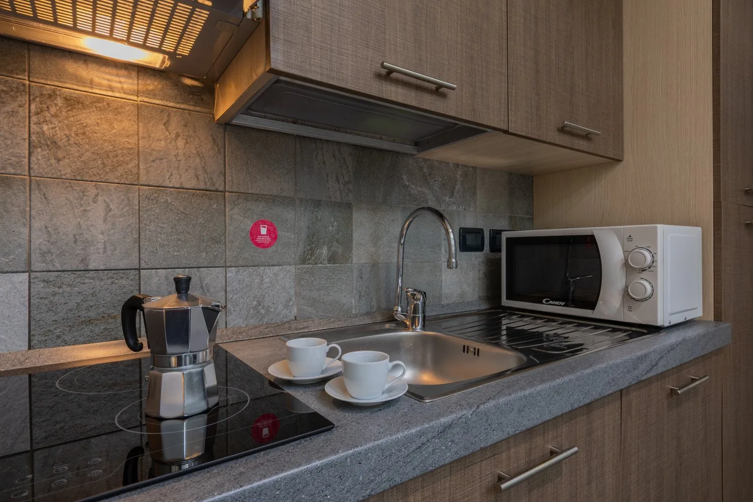 A compact kitchen with a stovetop, sink, and microwave.