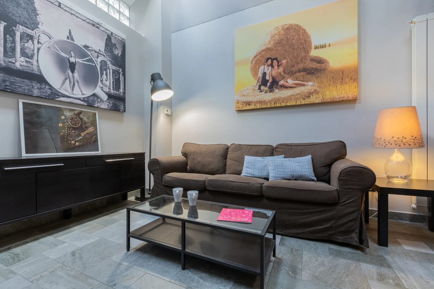 A living room with a sofa, coffee table, and artwork on the walls.