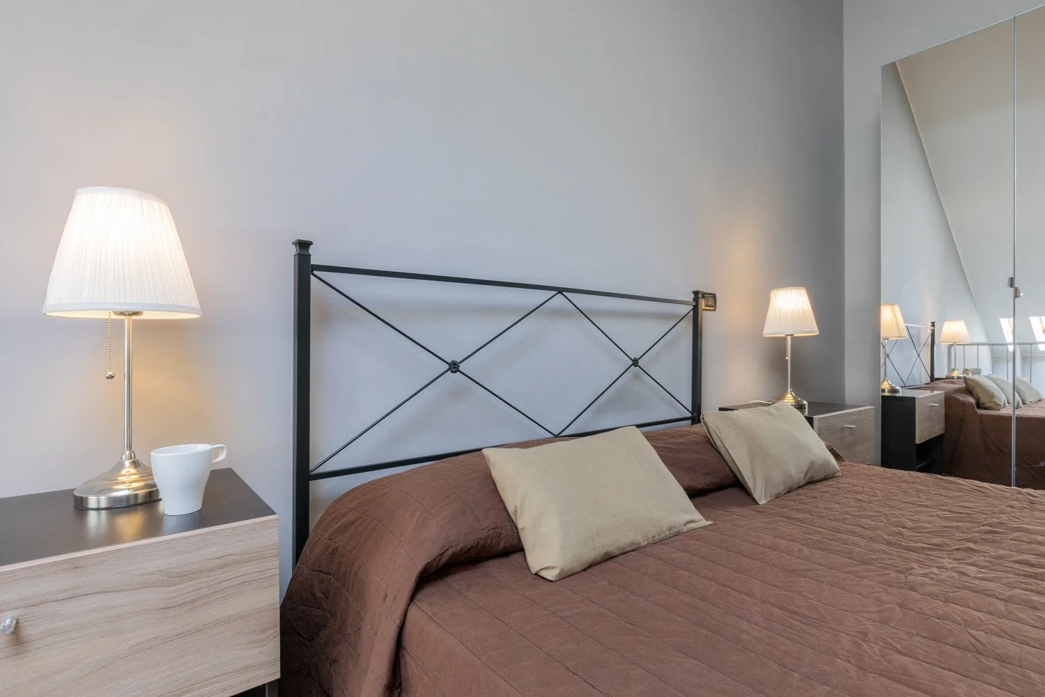 A bedroom with a bed, bedside tables, and lamps.
