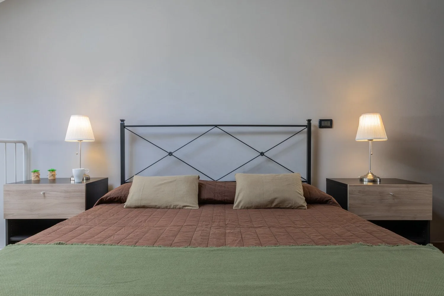 A bedroom with a large bed, bedside tables, and matching lamps.