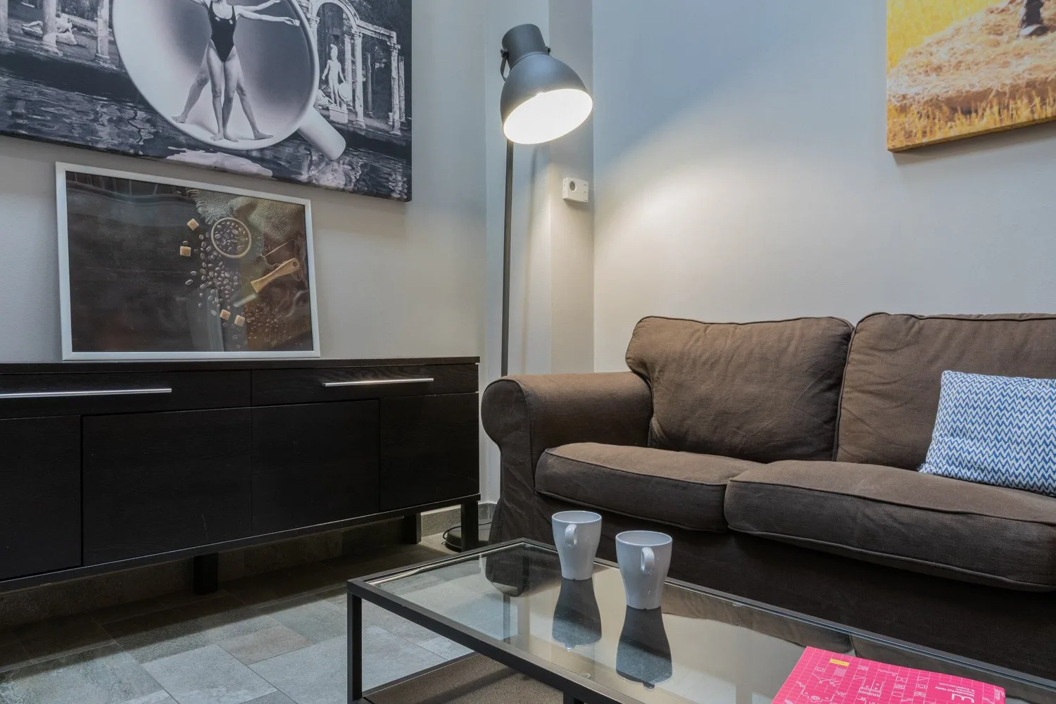 A living room with a dark sofa, glass coffee table, and floor lamp.