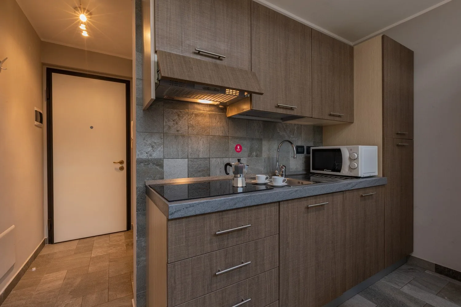 A compact kitchen with wood-tone cabinets, a countertop, and a microwave.