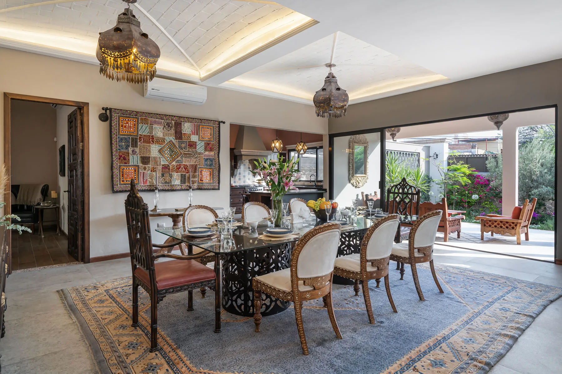 A dining area with a long table and chairs beneath decorative ceiling lights.