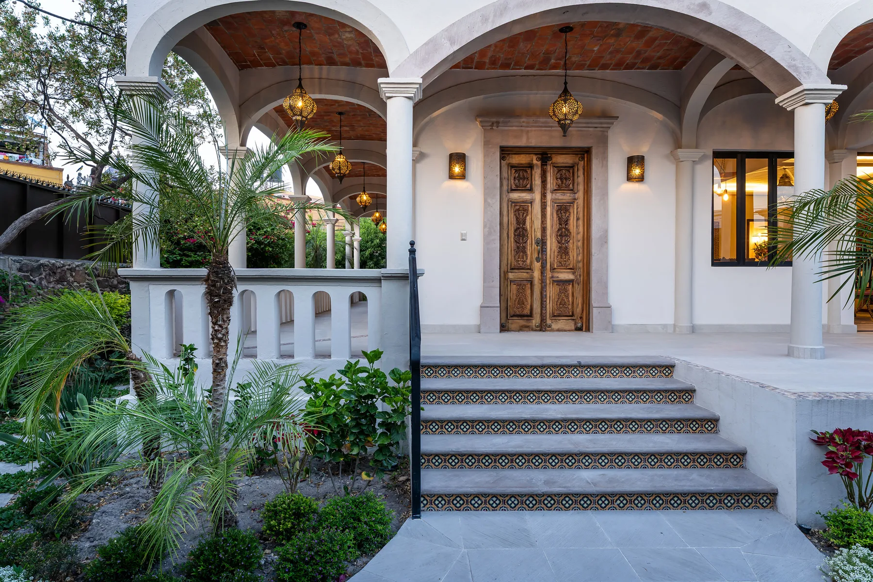 A covered entrance with arched openings, patterned steps, and a wooden door.