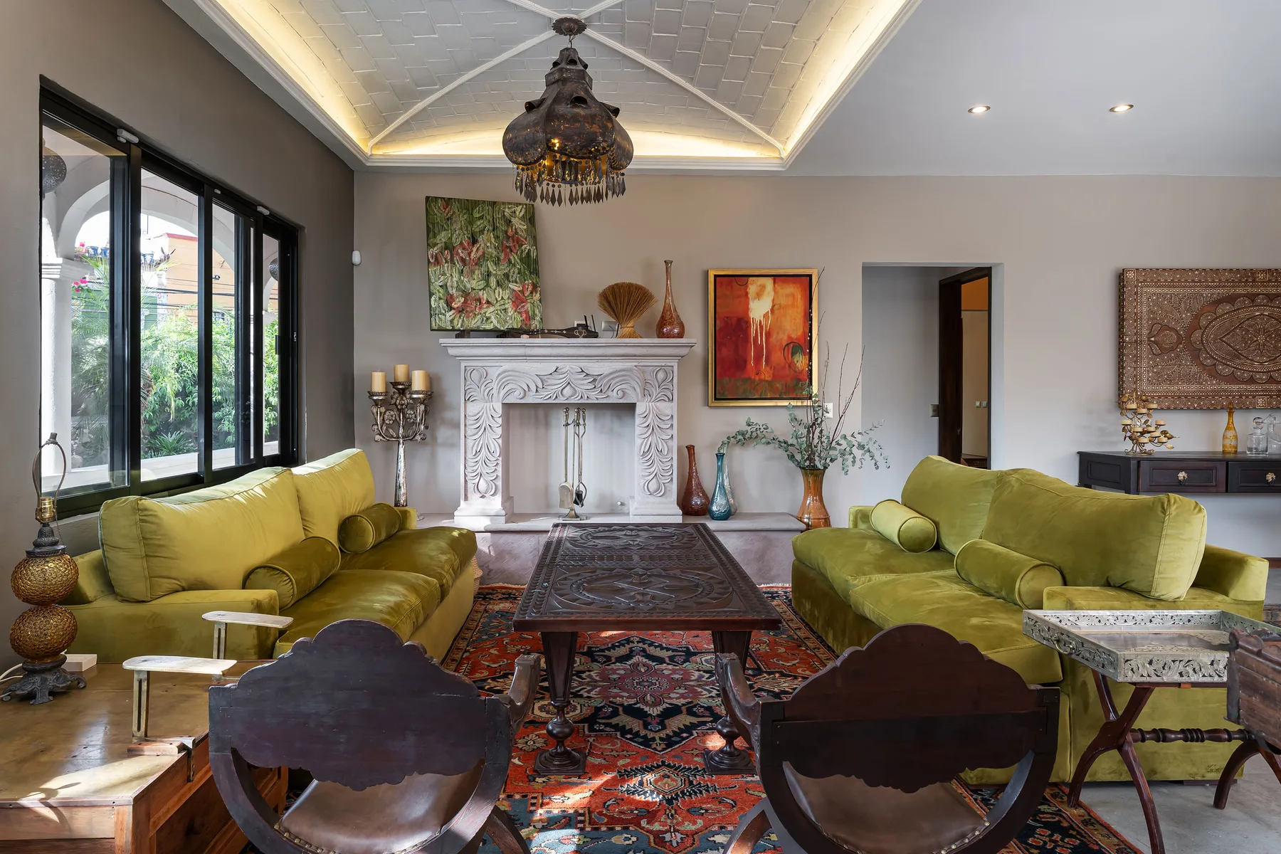 A living room with green seating arranged around a low table and fireplace.