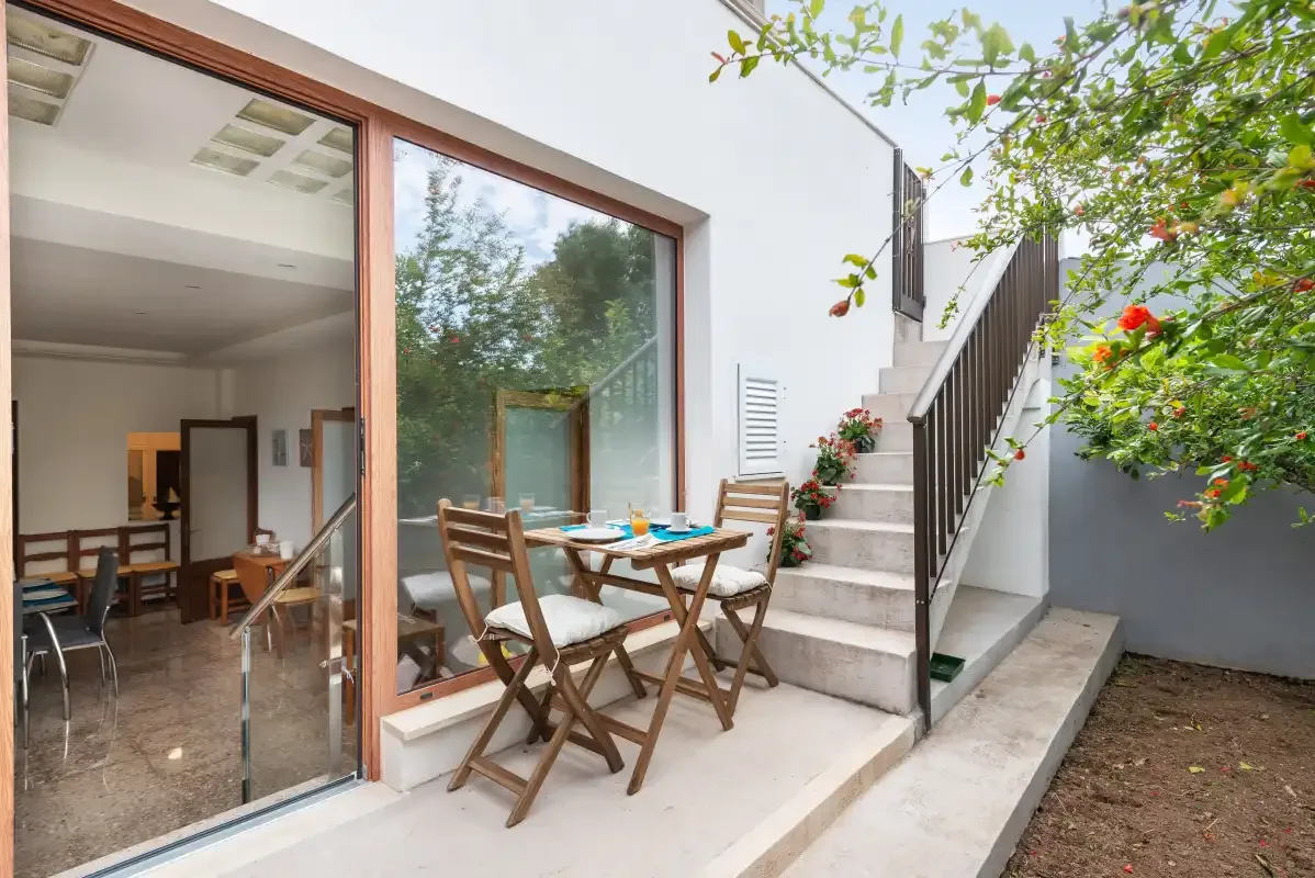 A patio dining area sits beside large glass doors and an outdoor staircase.