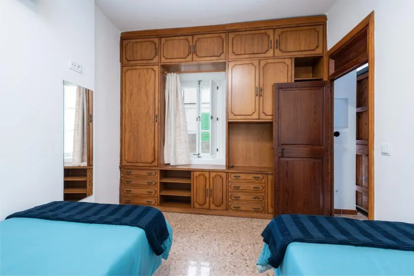 A bedroom with two beds and built-in wooden cabinets along the wall.