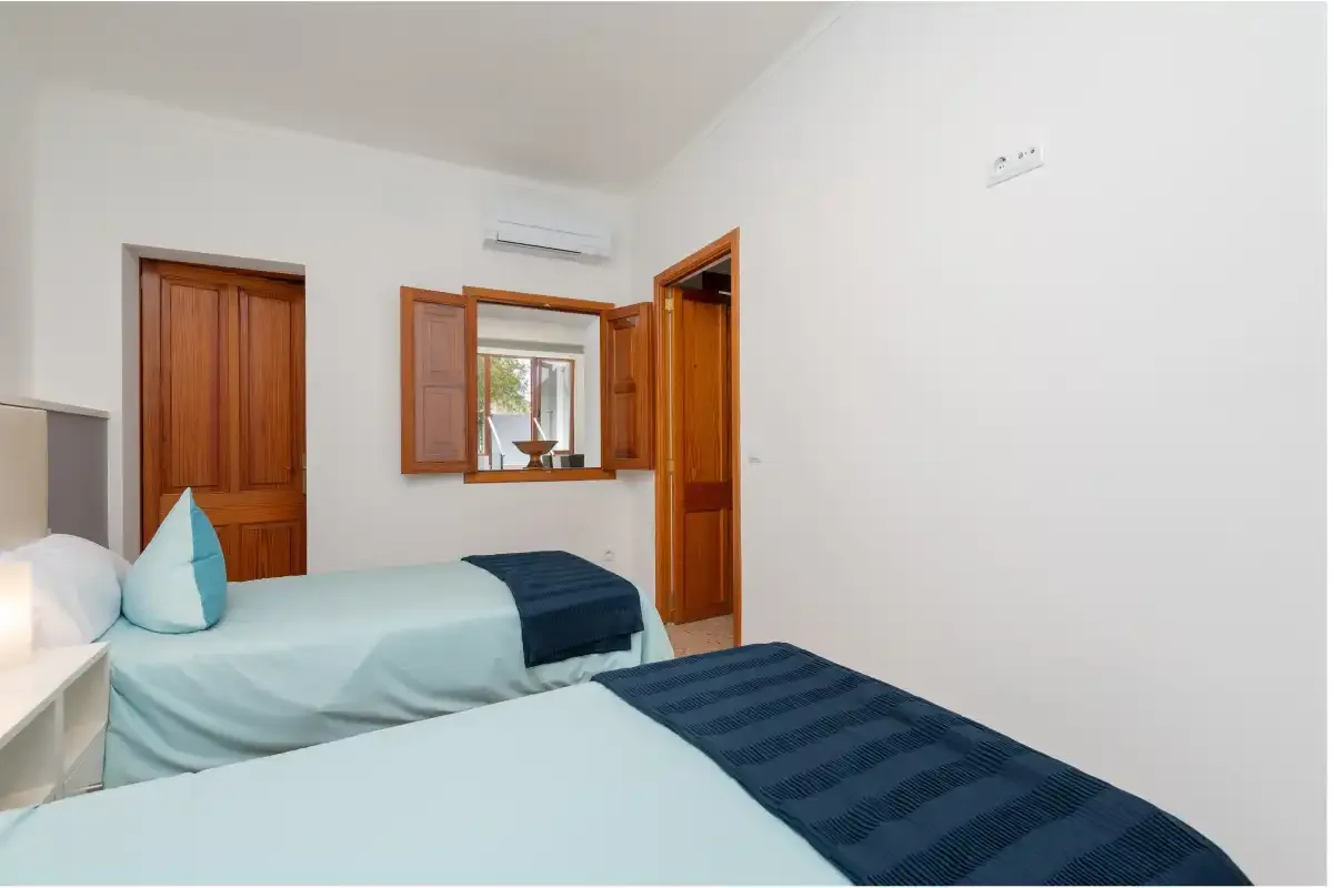 A bedroom with two beds and a window.