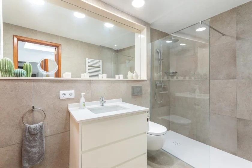 A bright bathroom with a white sink vanity and glass shower.