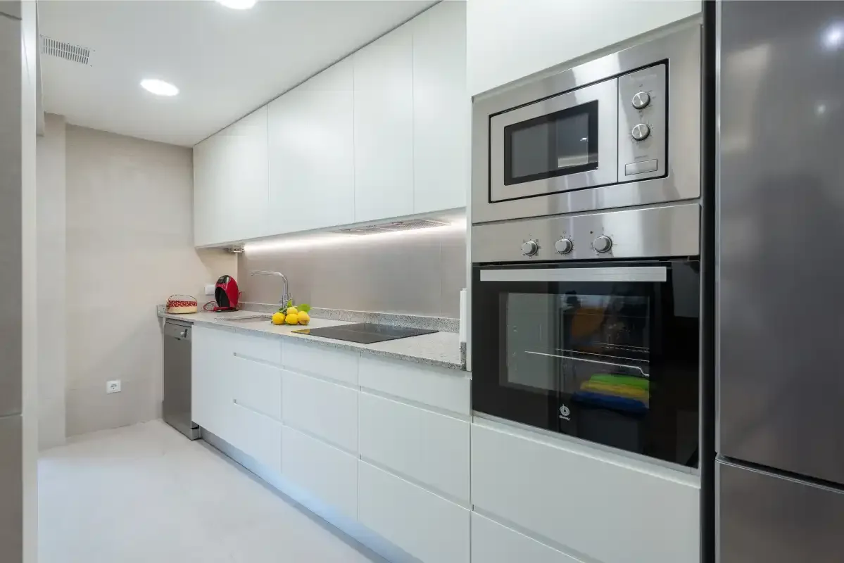 A bright modern kitchen with white cabinets and built-in appliances.