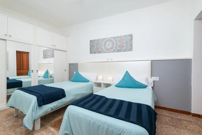 A bright bedroom with two beds dressed in pale blue bedding.