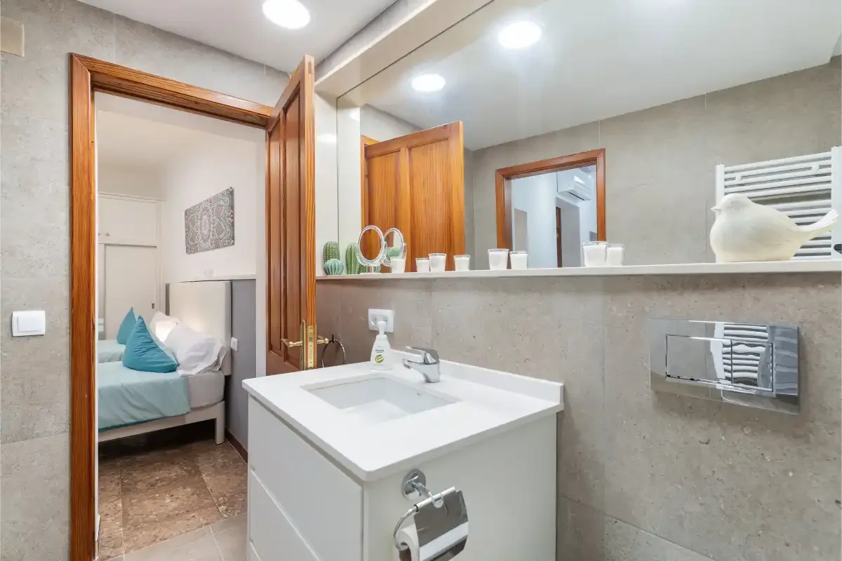 A bathroom with a white sink vanity and a large wall mirror.