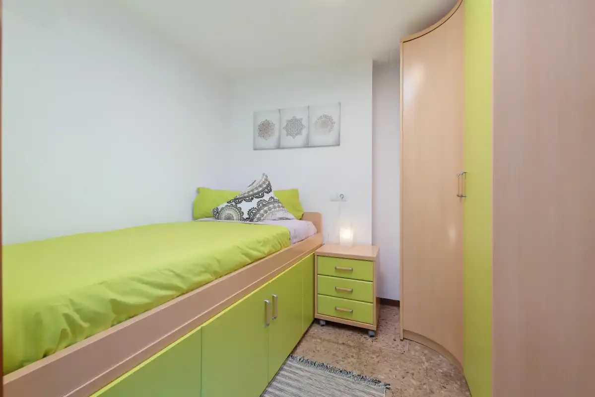 A bedroom with a bright green bed and matching storage.