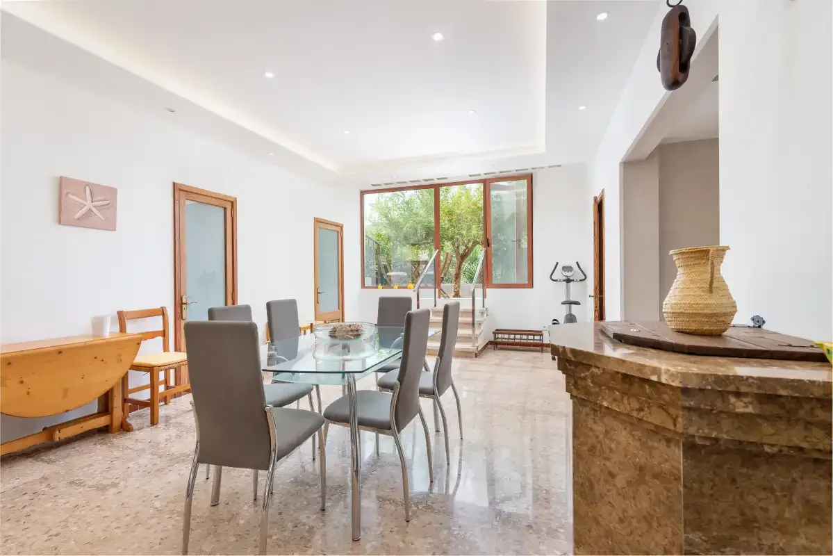 A bright dining area with a glass table and large windows.