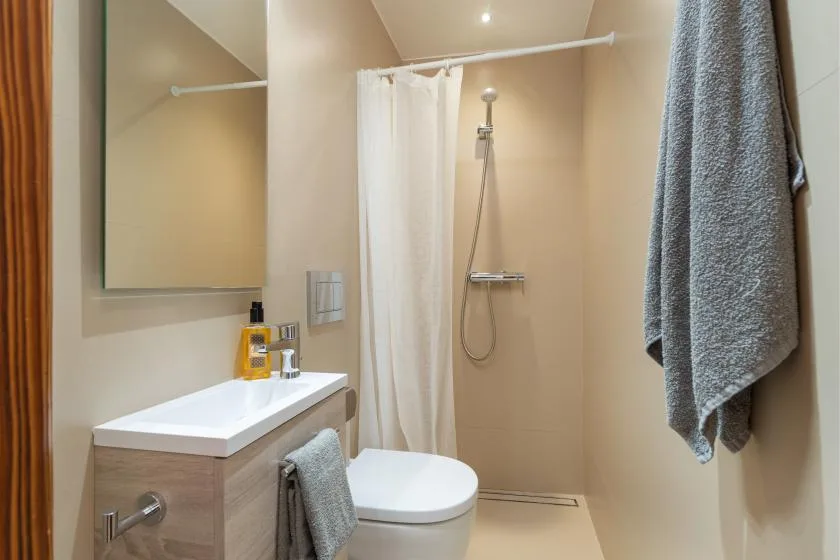 A bathroom with a sink, toilet, and shower behind a curtain.