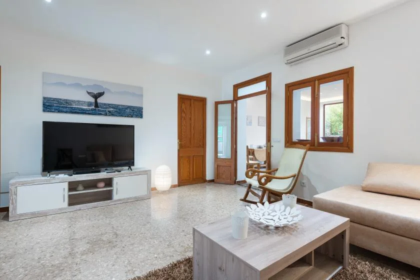 A bright living room with a television, seating, and a low coffee table.