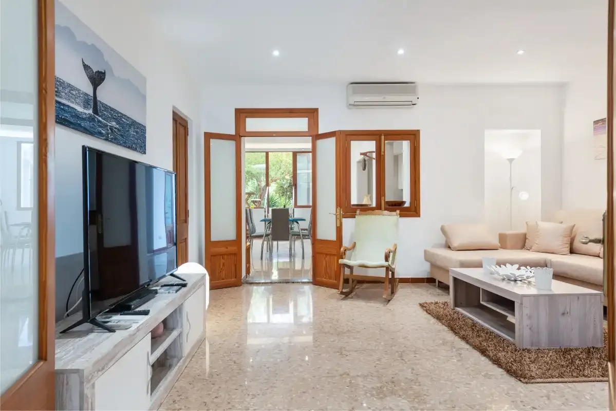 Bright living room with seating, a television, and glass doors opening to a balcony.