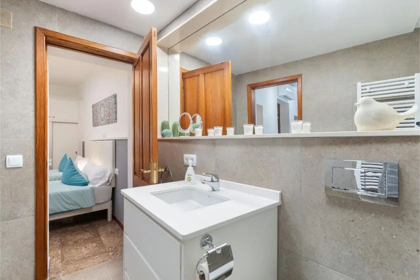 A bathroom with a white sink and a doorway opening toward a bedroom.