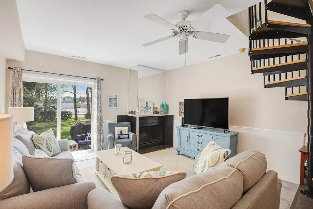 A living room with seating, a television, a fireplace, and glass doors opening to a patio.