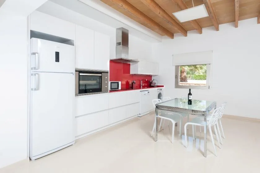 A bright kitchen and dining area with white cabinetry and a glass table.