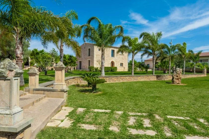 A stone building stands among palm trees and a green lawn.