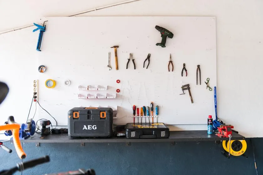 A workshop wall displays hand tools above a workbench.