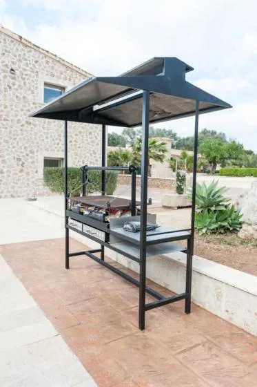 An outdoor cooking area with a covered grill beside a stone building.