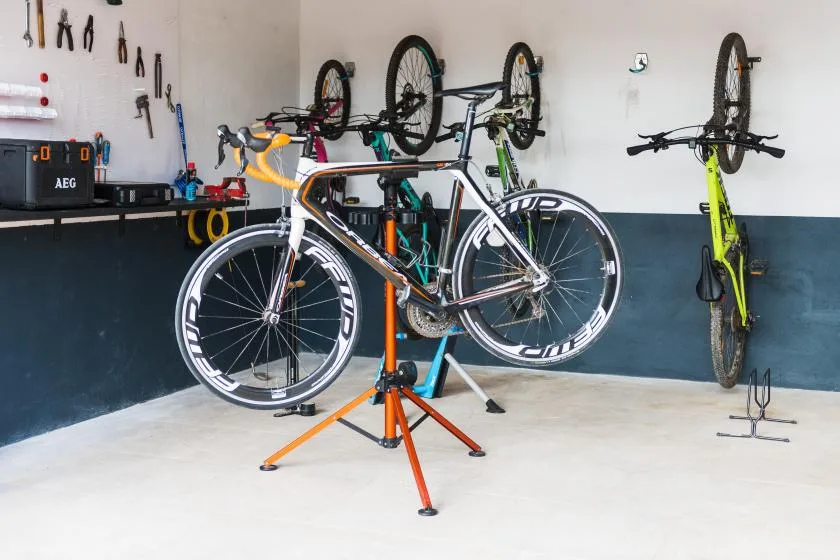 A bicycle workshop with bikes hanging on the wall and a road bike on a repair stand.