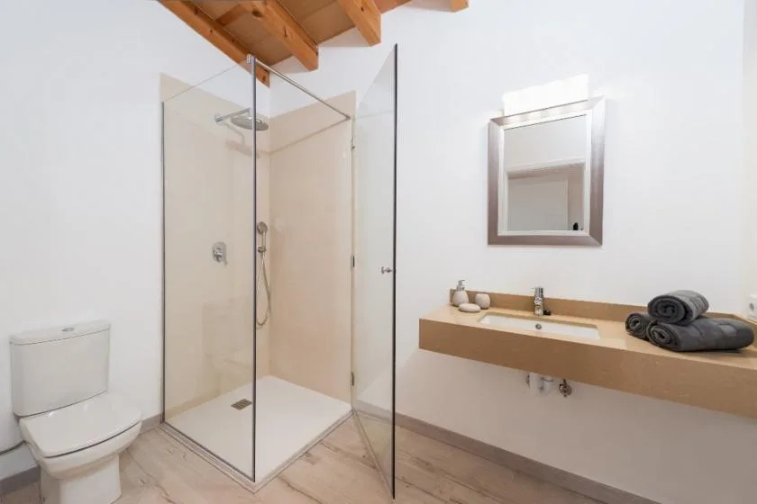 A bright bathroom with a glass shower and a long sink counter.