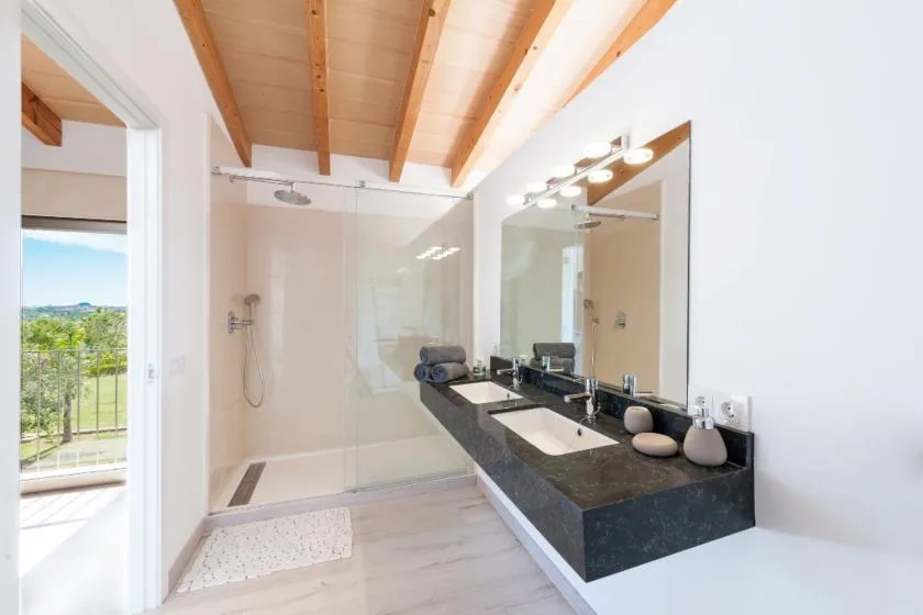 A bright bathroom with a walk-in shower and a double vanity.