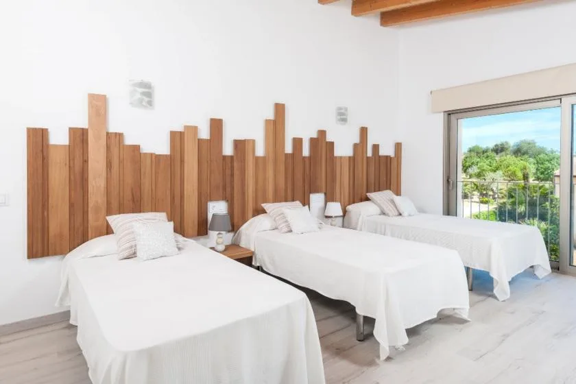 A bright bedroom with several beds arranged beneath a wooden wall feature.