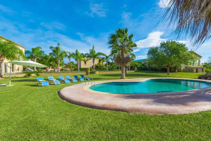 A landscaped outdoor pool area with lounge chairs on the surrounding lawn.
